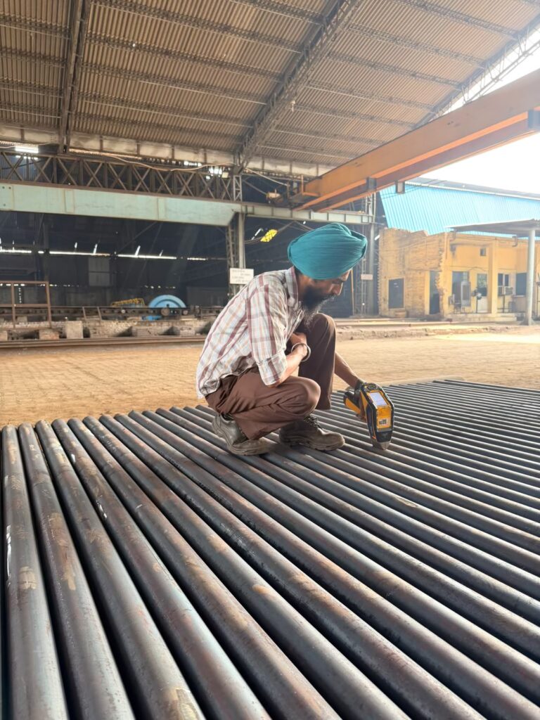 Inspector checking round bars with a handheld XRF analyser